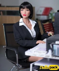 Margot Sex Doll 165cm Bonnet F en tenue de bureau, assise à un bureau moderne.