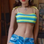 Taylor sex doll 150cm Bonnet B en short en jean et top rayé, posée debout près d'une armoire.