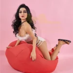 Alicia Sex Doll 150 cm IronTech en lingerie blanche posant à genoux sur un pouf rouge.