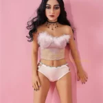 Alicia Sex Doll 150 cm IronTech Doll TPE debout, lingerie rose et collier noir, fond rose.