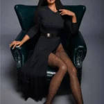 Alicie Sex Doll 168 cm IronTech assise sur fauteuil, robe noire, jambes croisées.