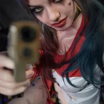 Amara Sex Doll 166 cm IronTech, posée avec un pistolet, tenue rouge et blanche, regard intense.