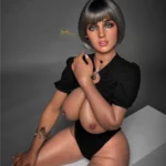 Amova Sex Doll 165 cm IronTech, assise, cheveux courts, tenue noire, fond gris.