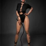 Amova Sex Doll 165 cm IronTech en tenue noire, pose dominante avec fouet, cheveux courts.