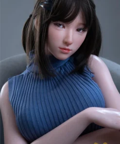 Anabelle Sex Doll 166 cm IronTech en pull bleu, pose assise, cheveux bruns avec barrette.