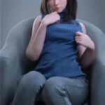 Anabelle Sex Doll 166 cm IronTech Doll assise, vêtue d'un pull bleu et pantalon gris.
