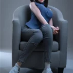 Anabelle Sex Doll 166 cm IronTech assise sur fauteuil, tenue décontractée, ambiance neutre.