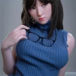 Anabelle Sex Doll 166 cm en robe bleue sans manches, tenant des lunettes devant sa poitrine.