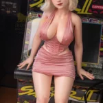 Aurélia Sex Doll 165 cm IronTech Doll en robe rose devant une borne d'arcade rétro.