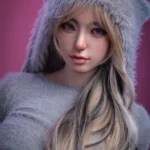 Avalyn Sex Doll 164 cm IronTech, vêtue d'un pull gris à capuche, cheveux longs, fond rose.