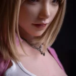 Ellya Sex Doll 169 cm IronTech Doll, gros plan visage réaliste, cheveux blonds, chemise rose.