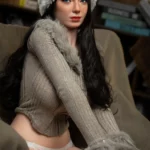 Ellye Sex Doll 165 cm IronTech Doll en pull beige et bonnet blanc, assise sur un canapé.