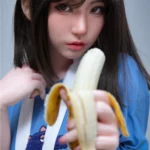 Elyzabelle Sex Doll 164 cm IronTech, tenue bleue, tenant une banane épluchée.