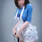 Elyzabelle Sex Doll 164 cm en tablier à motifs cœurs, pose debout, regard vers le bas.