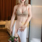 Emmalia Sex Doll 167 cm en lingerie beige, tenant une serviette et des roses, pose debout.