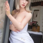 Emmalia Sex Doll 167 cm IronTech, pose debout, serviette blanche, intérieur moderne.