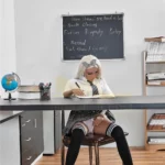 Emmarose Sex Doll 150 cm IronTech Doll TPE assise à un bureau, tenue d'écolière.