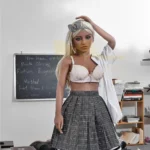 Emmarose Sex Doll 150 cm IronTech en tenue d'écolière, posée sur un bureau en classe.