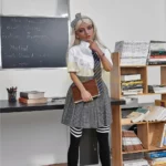 Emmarose Sex Doll 150 cm IronTech Doll TPE en tenue d'écolière, debout près d'une étagère.