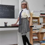 Emmarose Sex Doll 150 cm IronTech Doll TPE en uniforme scolaire, debout près d'une bibliothèque.