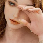 Enchantia Sex Doll 165 cm IronTech, gros plan visage réaliste, main délicatement posée sur le front.