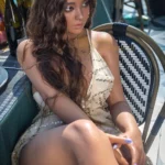 Lilabelle Sex Doll 164 cm IronTech assise en robe d'été, cheveux longs bouclés, extérieur.