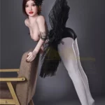 Lisette Sex Doll 150 cm IronTech Doll TPE en pose élégante, appuyée sur une chaise, jupe noire volumineuse.