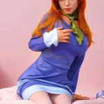 Lizette Sex Doll 167 cm IronTech en robe bleue, posée assise sur fond rose.