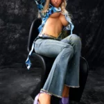 Lovabelle Sex Doll 167 cm IronTech Doll assise, chapeau violet, chemise bleue, jeans et talons violets.