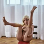 Lulaine Sex Doll 150 cm IronTech posée sur un banc, jambe levée, devant une fenêtre.