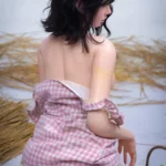Lumara Sex Doll 166 cm IronTech Doll en robe vichy rose, posée de dos sur fond de paille.