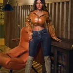 Luméa Sex Doll 165 cm IronTech en tenue moderne, debout près d'un fauteuil.