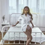 Luminova Sex Doll 150 cm IronTech Doll TPE debout près d'un lit, chemise blanche ouverte.