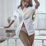 Luminova Sex Doll 150 cm IronTech en chemise blanche, posée sensuellement contre un lit.