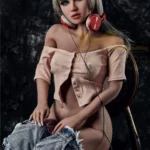 Lumira Sex Doll 150 cm IronTech avec chemise rose et casque audio, posée assise.