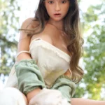 Mabilie Sex Doll 167 cm IronTech en robe blanche, posée en extérieur avec vue en contre-plongée.