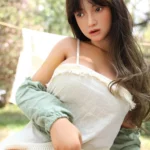 Mabilie Sex Doll 167 cm IronTech Doll en robe blanche, posée dans un jardin ensoleillé.