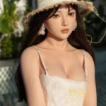 Poupée Ninabelle Sex Doll 166 cm en robe blanche, chapeau de paille, posée à l'extérieur.