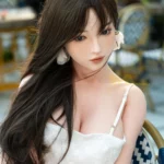 Ninabelle Sex Doll 166 cm IronTech en robe blanche, assise, regard vers la gauche.