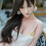 Ninabelle Sex Doll 166 cm IronTech Doll en robe blanche, assise, cheveux bruns lâchés.