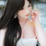 Ninabelle Sex Doll 166 cm en robe blanche, cheveux longs, pose assise élégante.
