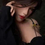 Pixie Sex Doll 166 cm IronTech Doll en robe noire, regard intense, main sur visage.