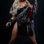 Rosalynn Sex Doll 164 cm en tenue guerrière, tenant épée et bouclier, pose dynamique.