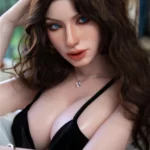 Séducheveux Sex Doll 166 cm IronTech Doll en robe noire, pose assise élégante, cheveux bruns ondulés.