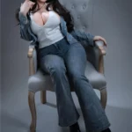 Vélyna Sex Doll 165 cm IronTech assise sur fauteuil, tenue décontractée en denim et top blanc.