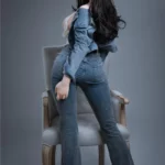 Vélyna Sex Doll 165 cm IronTech en jean, posée de dos sur une chaise en bois.