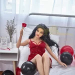 Zadie Sex Doll 150 cm IronTech en robe rouge, allongée sur un lit, tenant une rose.