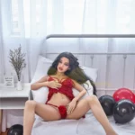 Zadie Sex Doll 150 cm IronTech Doll TPE en lingerie rouge sur lit, pose décontractée.