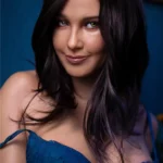 Zoélie Sex Doll 166 cm IronTech, cheveux bruns, lingerie bleue, sourire subtil, fond bleu.