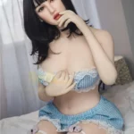 Alia Sex Doll 159 cm IronTech en lingerie bleue, assise sur un lit, cheveux noirs courts.